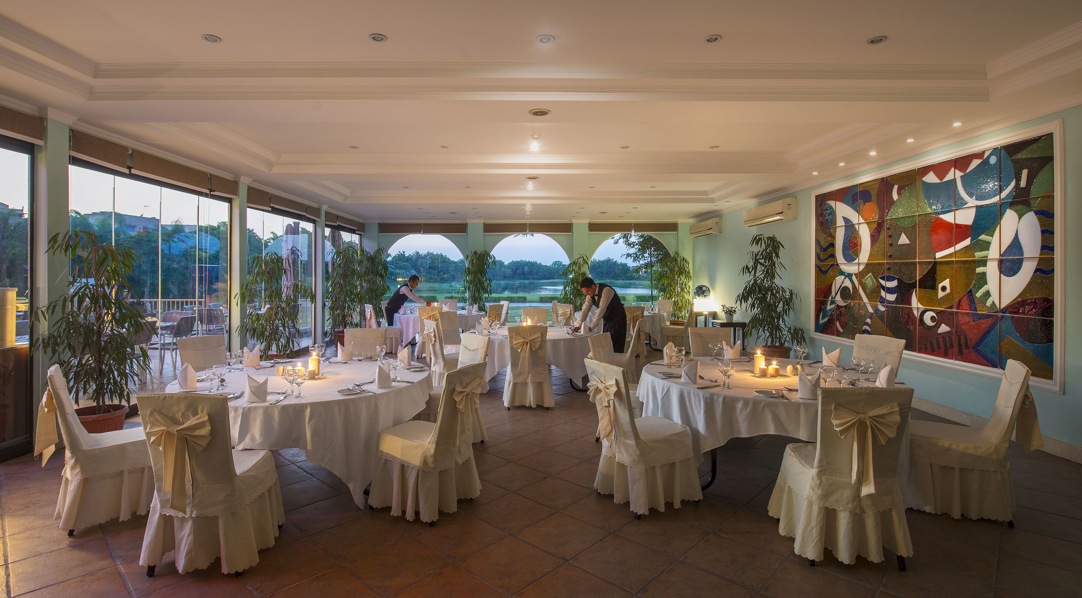 A banquet hall with round tables, white tablecloths, and chairs with bows.
