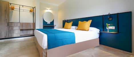 Una habitación de hotel moderna con una cama grande, un armario de madera, un espejo redondo y un estante pequeño con objetos decorativos.