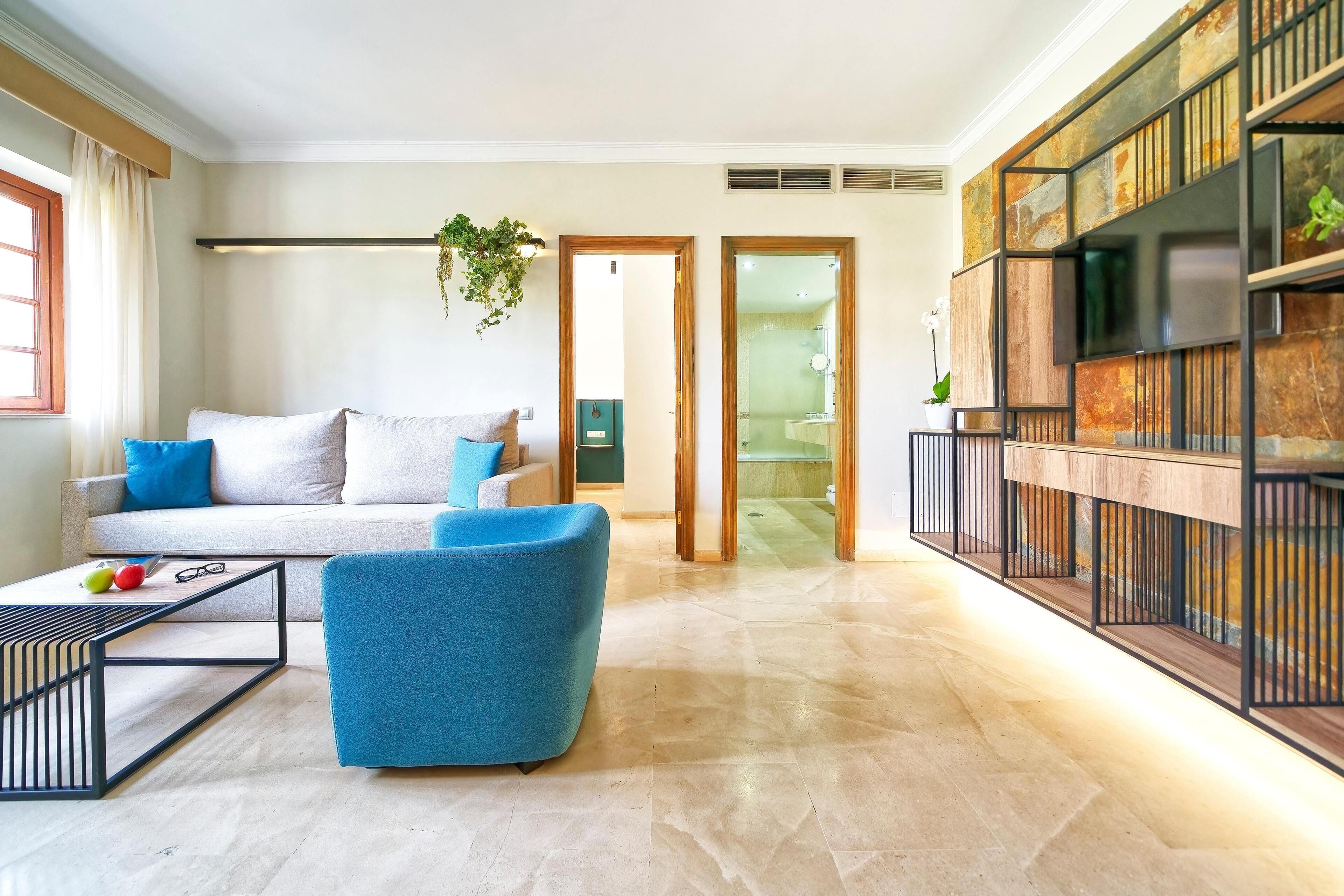 Una sala de estar moderna con un sofá, un sillón azul, una mesita de centro y una estantería.