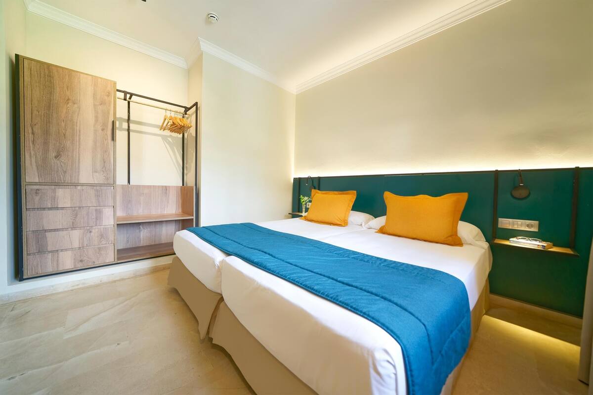 A bedroom with a bed, a wooden wardrobe, and a hanging rack.