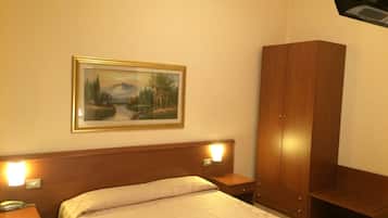Ein Hotelzimmer mit Bett, Nachttischlampen, einem Kleiderschrank und einem Bild an der Wand.