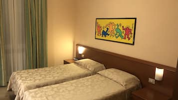 Ein Hotelzimmer mit zwei Betten, einem Nachttisch mit Telefon, einer Wandleuchte und einem farbenfrohen Kunstwerk.