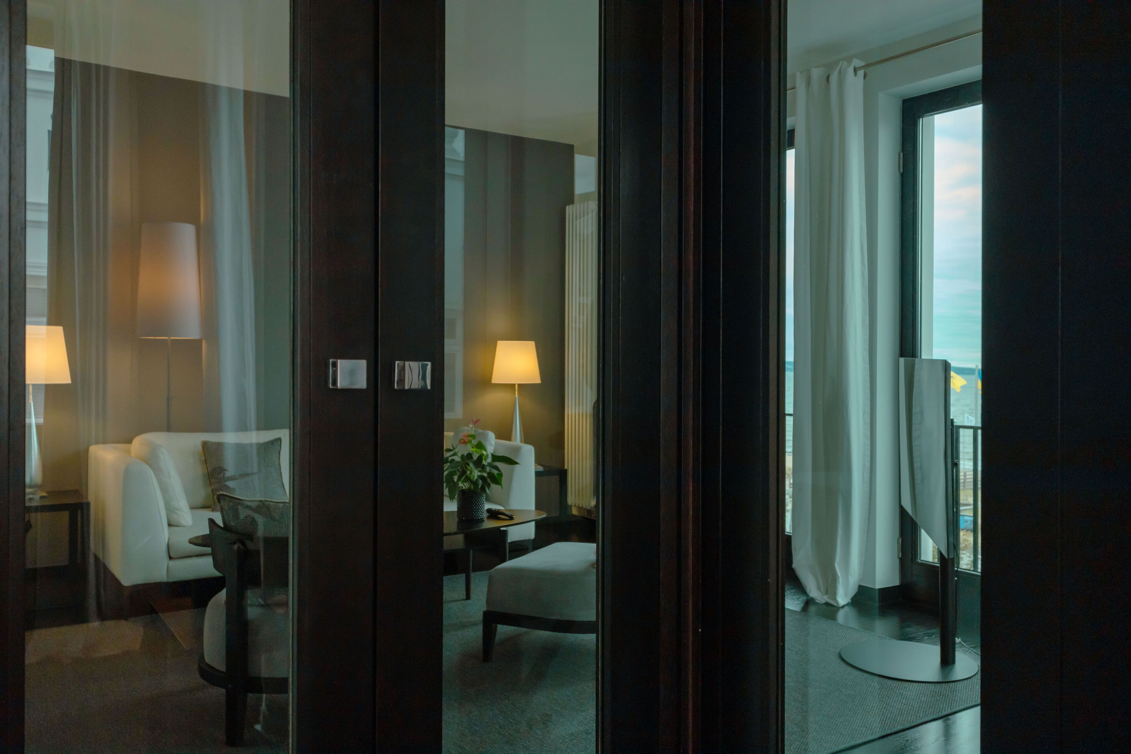 Una habitación de hotel con sofá, sillón y una mesita de noche con lámpara.