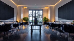 Un comedor moderno con una mesa central, sillas tapizadas de color negro y vistas a través de amplios ventanales.