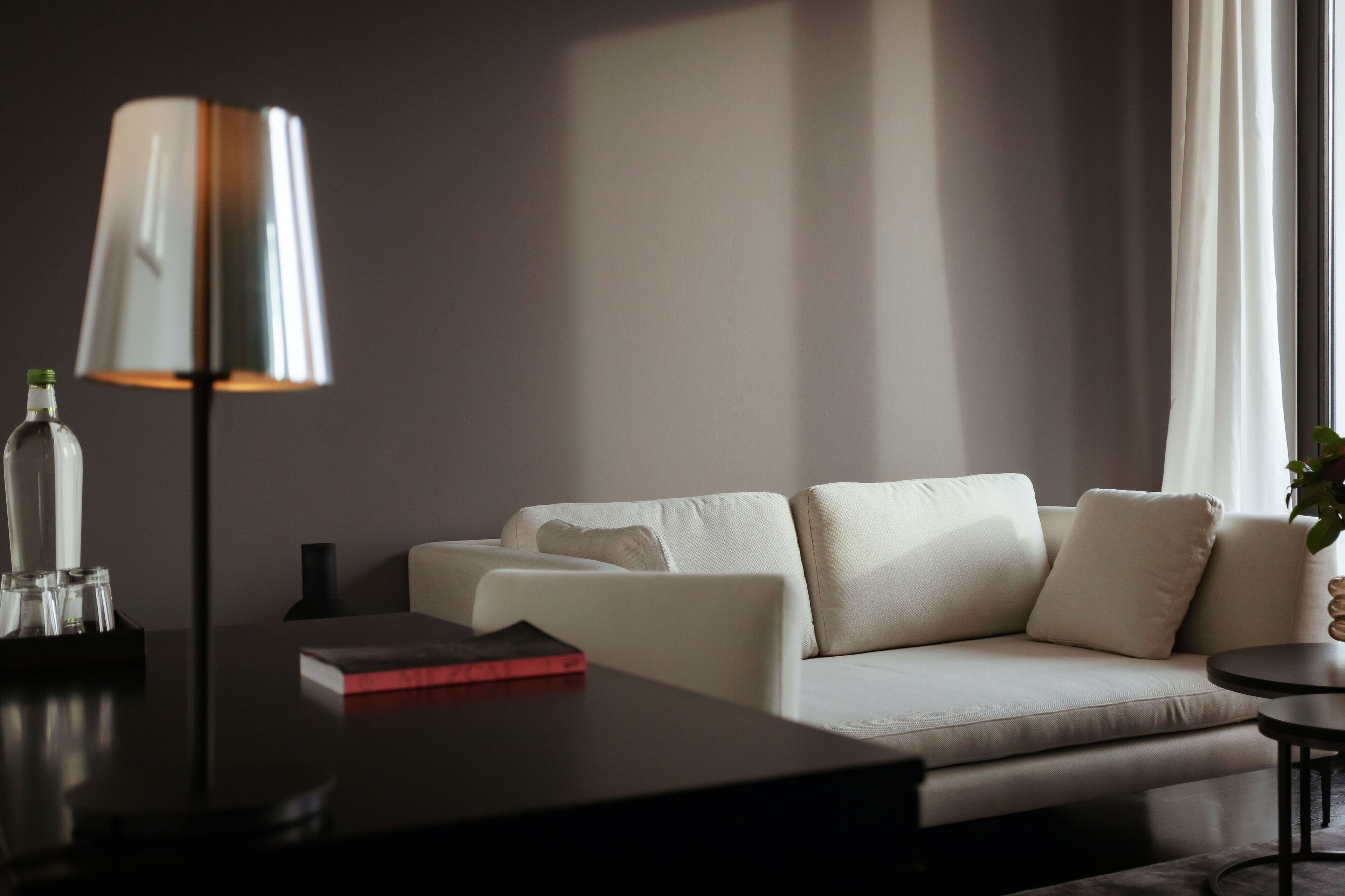 Una sala de estar moderna con un sofá, una mesa de centro, una lámpara y una mesita auxiliar.