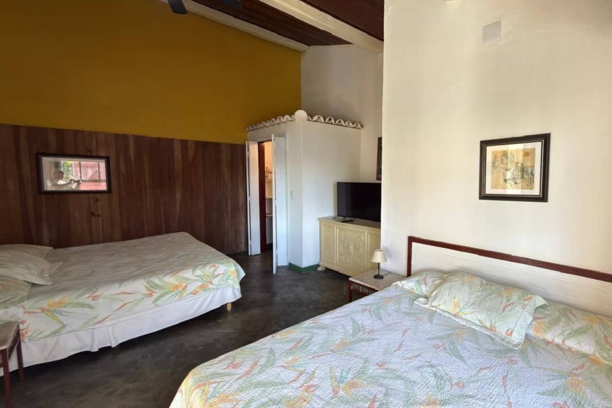 A hotel room with two single beds, a television, and a small cabinet.