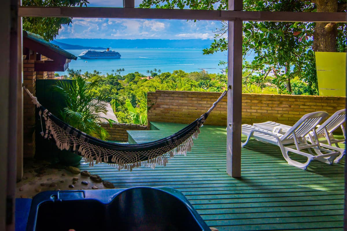 A hammock, lounge chairs, and a view of the ocean with a cruise ship.