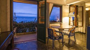 A balcony with a table and chairs, a view of the ocean, and a lamp on the table. -  Maison Joly Residence (Ilhabela)