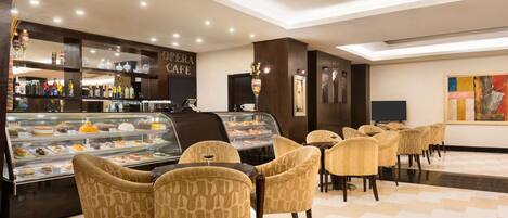 Un café moderno con una vitrina de pasteles, sillas estampadas y una zona de bar con botellas de licor.