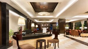 A lobby with a reception desk, seating area, and a ceiling with a unique design.