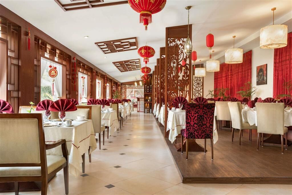 A restaurant with multiple tables and chairs, red lanterns, and traditional decor.