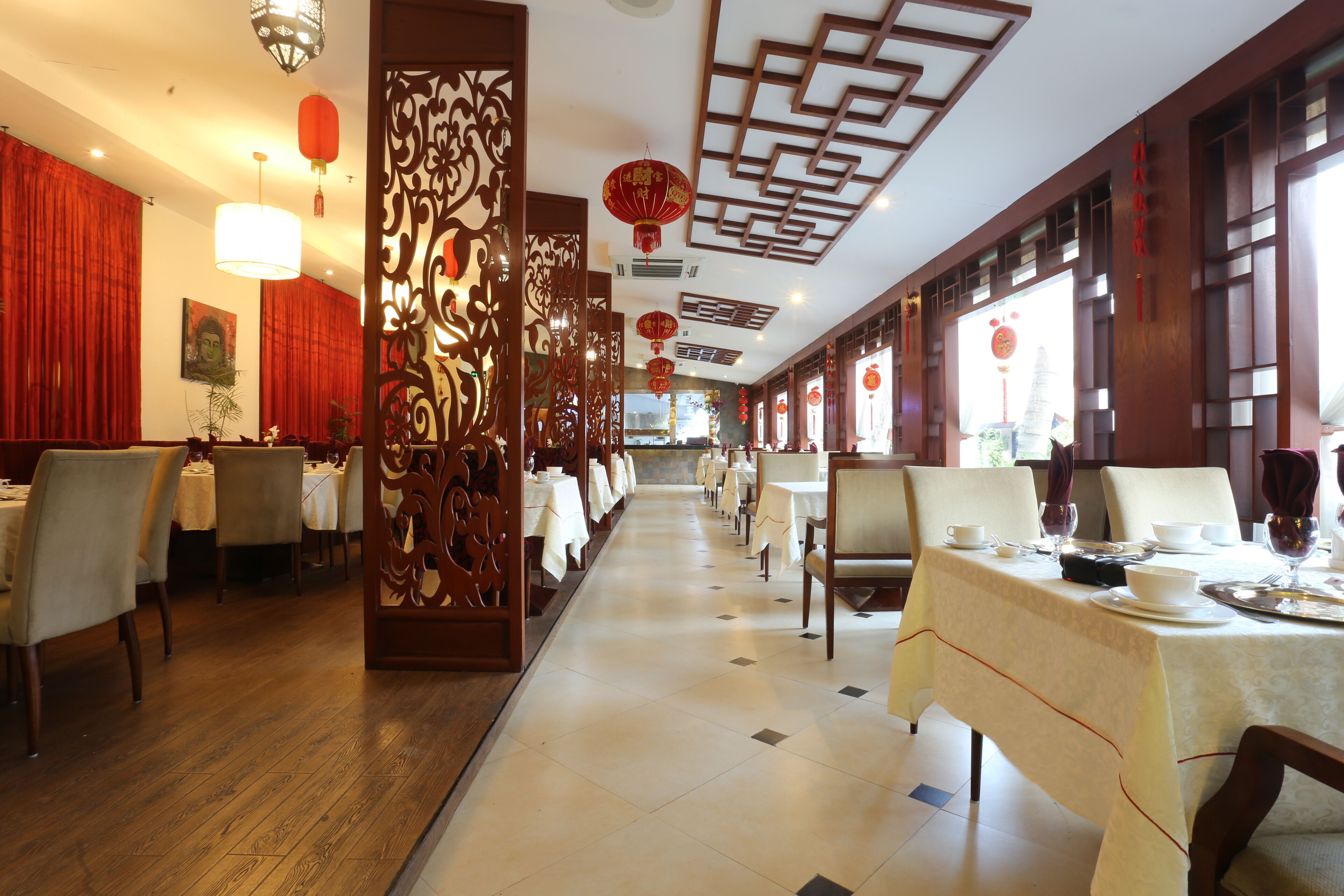 Un restaurante con paneles de madera, faroles rojos y mesas vestidas con manteles blancos.