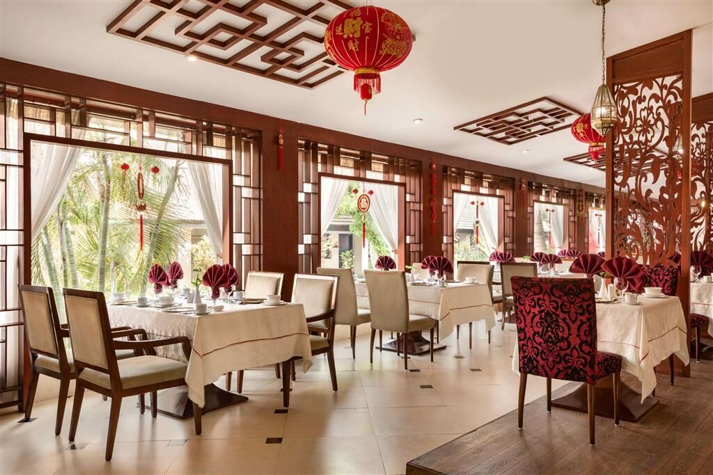 A restaurant with wooden furniture, red lanterns, and large windows.