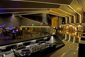 A modern bar area with a Pioneer DJ turntable setup, bar stools, and a reflective floor. - Radisson Blu Bengaluru Outer Ring Road (Bengaluru)