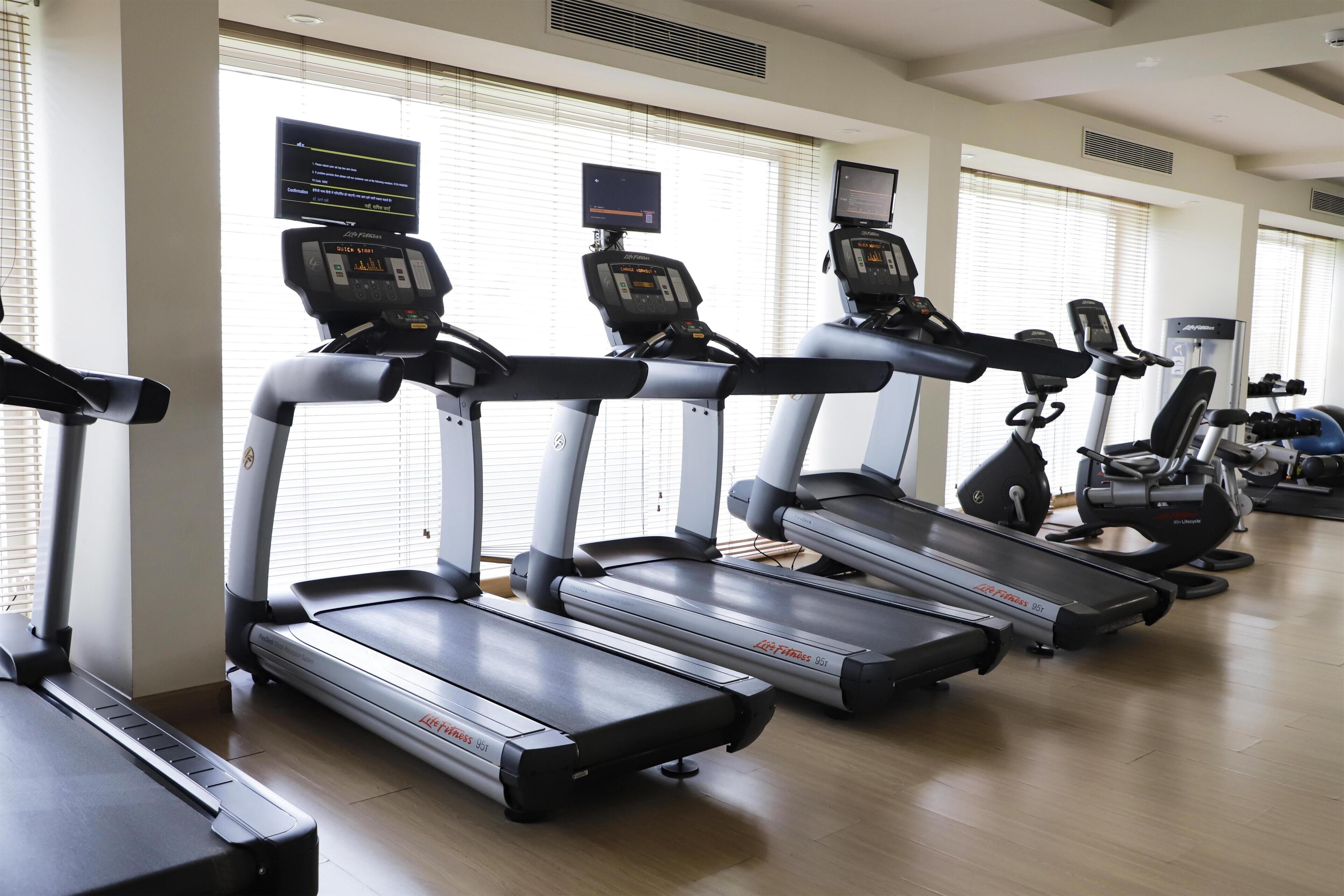 A gym with multiple treadmills, exercise bikes, and weight machines.