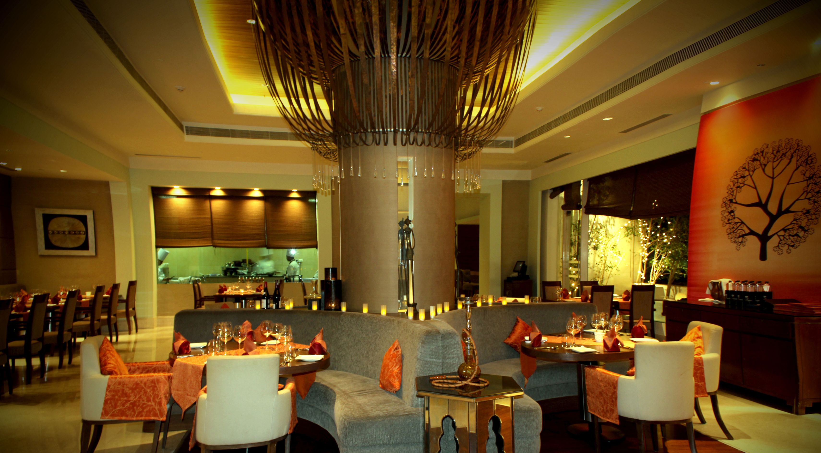 Un restaurante con varias mesas, sillas y una columna decorativa central.