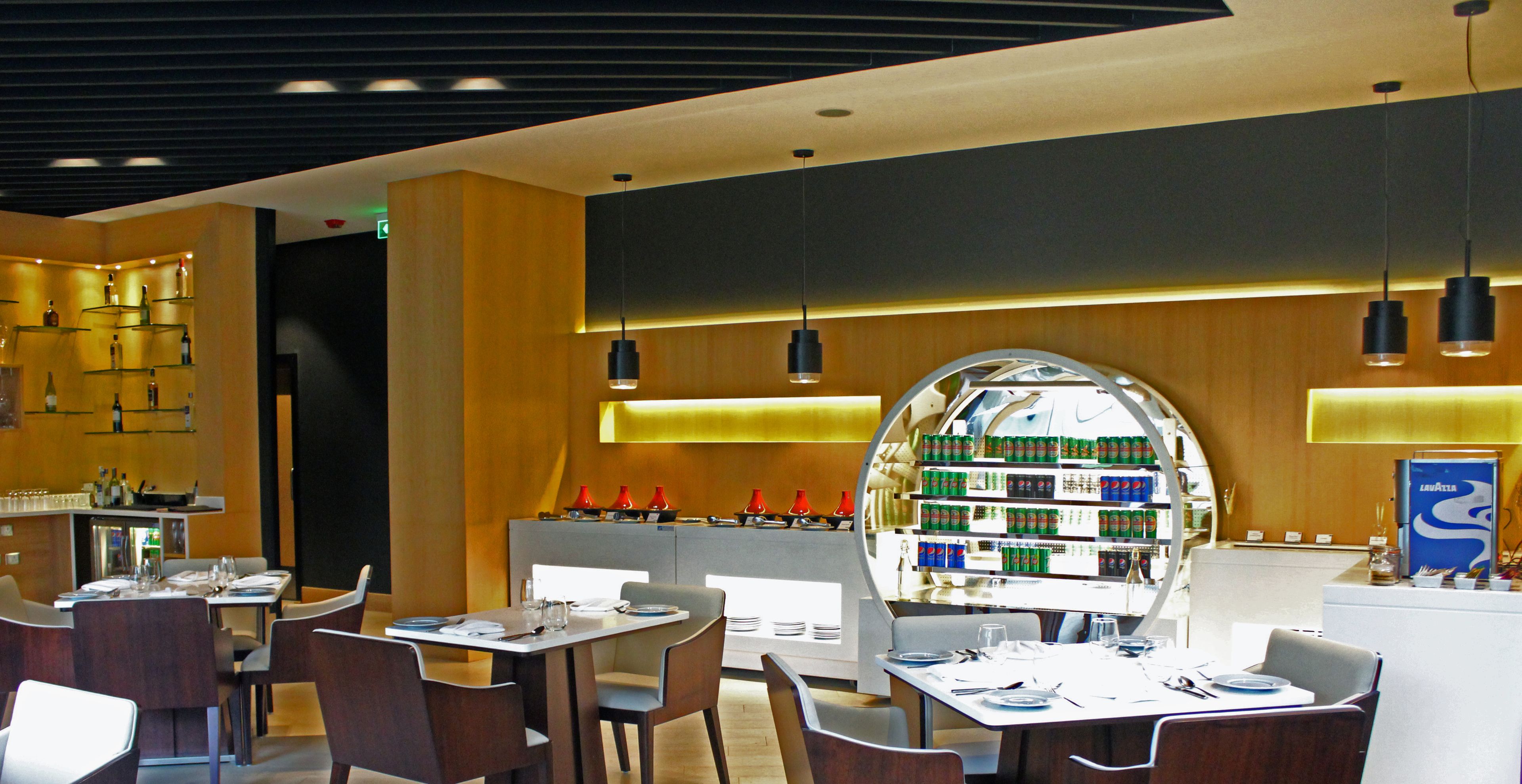 Un restaurant modern amb una barra central, diferents disposicions de seients i una presentació de begudes.
