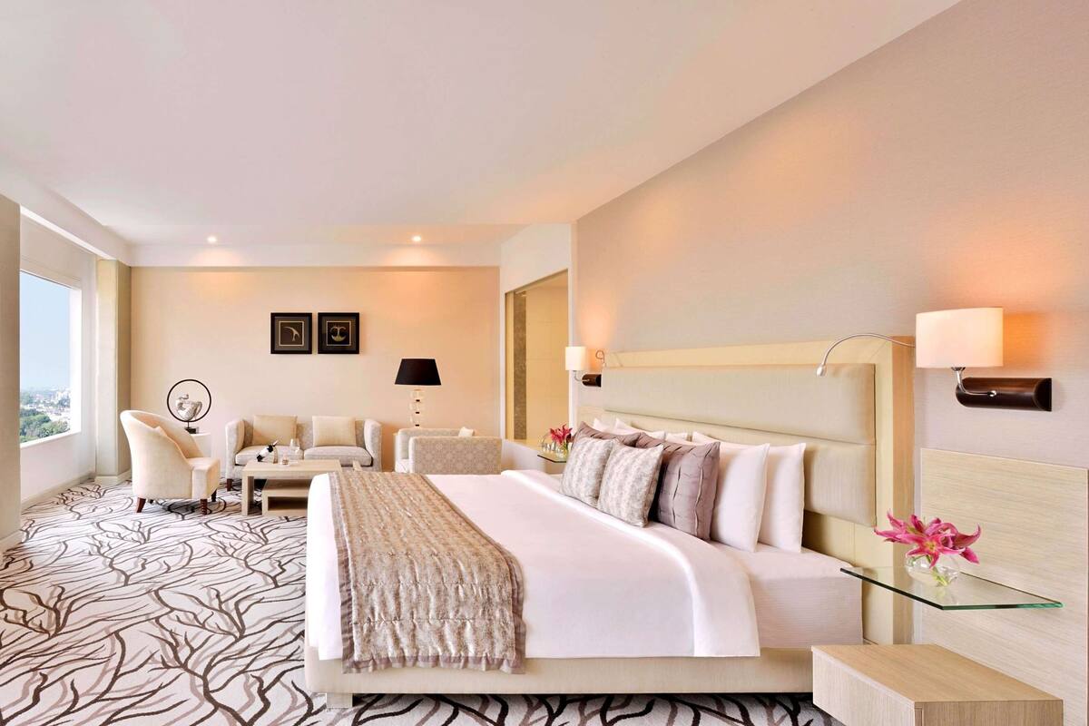 Quarto de hotel com uma cama grande, uma escrivaninha, uma cadeira, uma televisão e vista para a cidade.