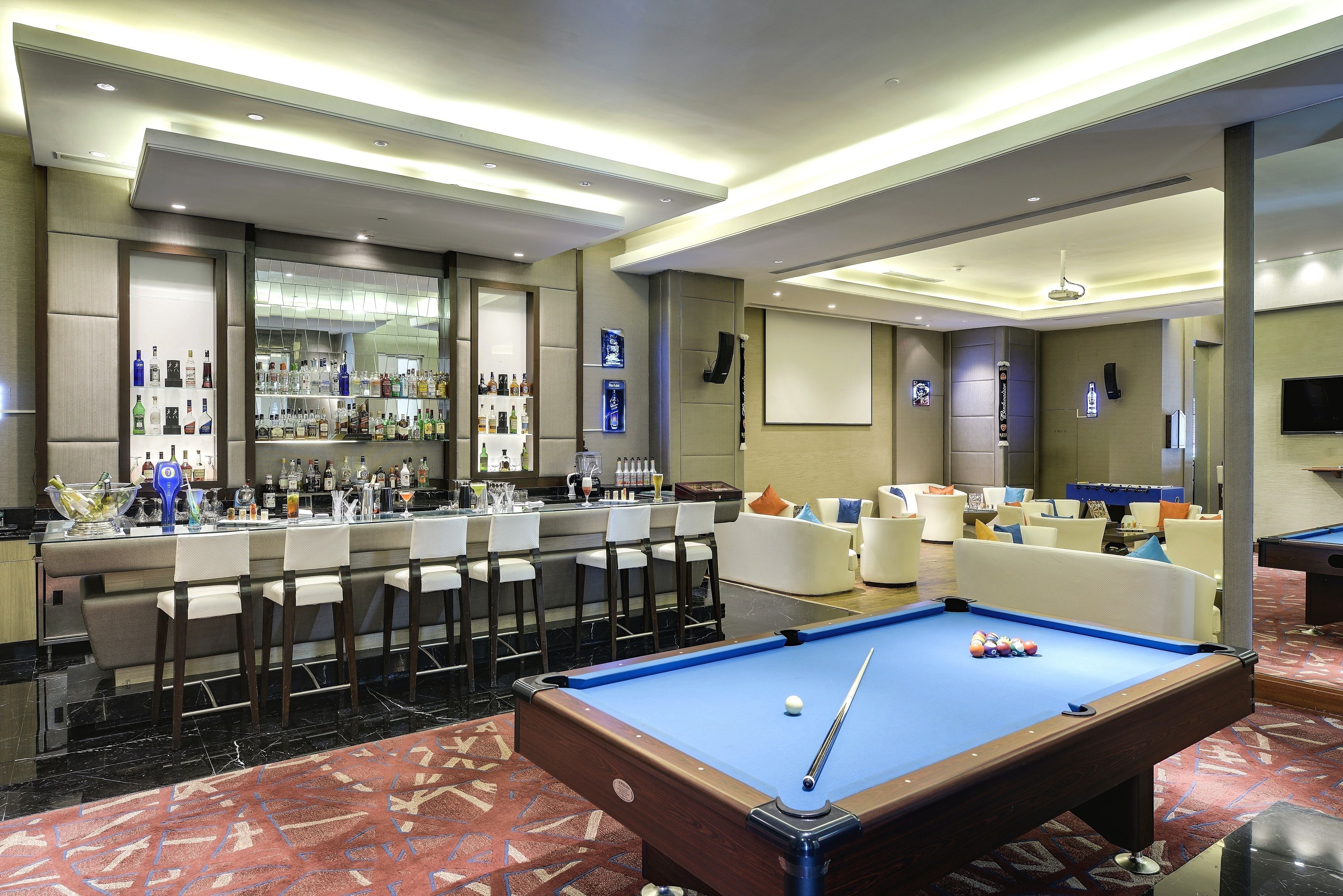 A pool table, bar area, and seating in a hotel room.