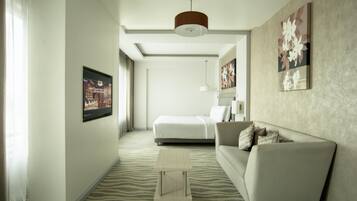 Una habitación de hotel moderna con cama, sofá, una mesita y un amplio ventanal.