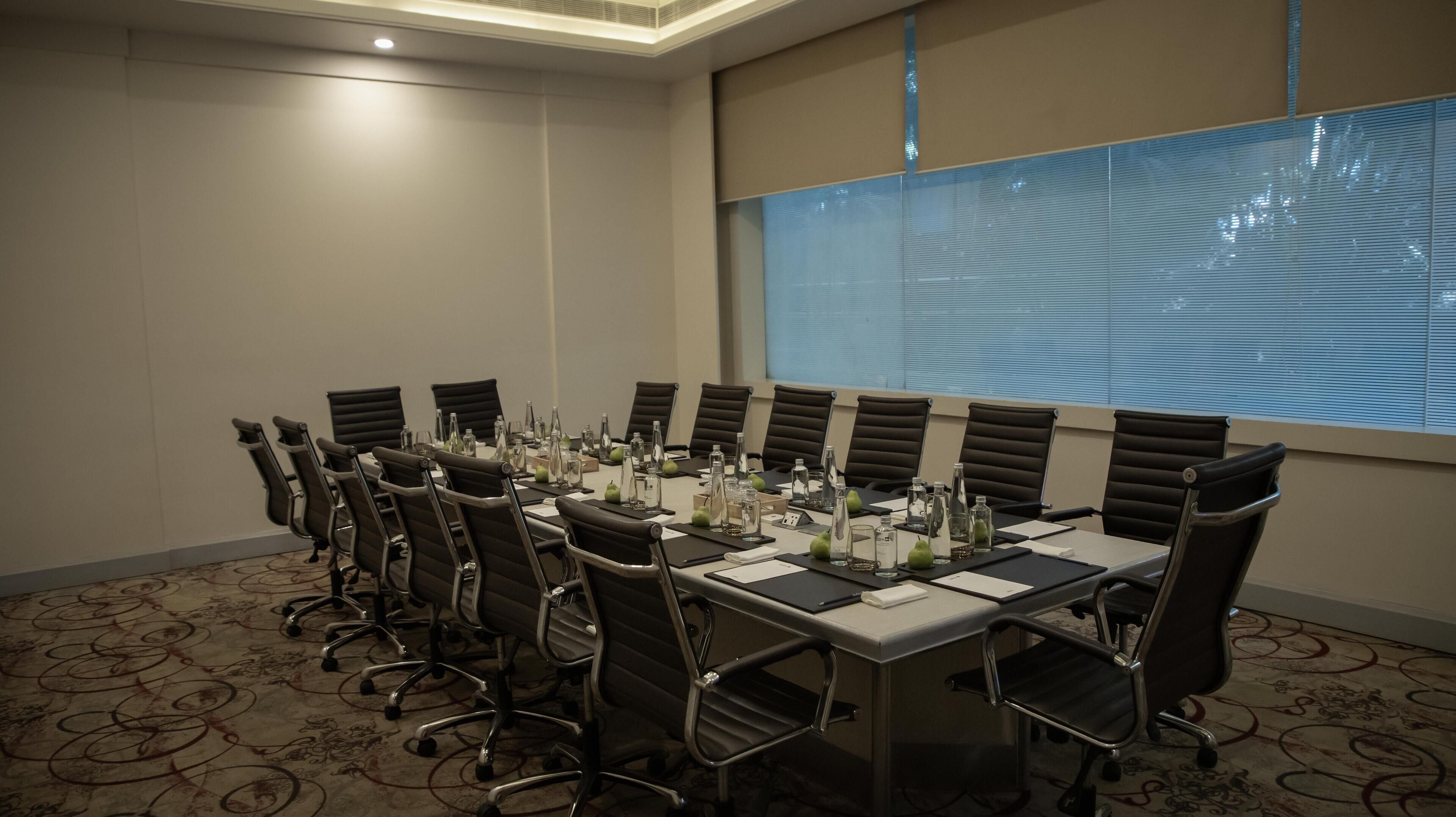 A conference room with a long table, chairs, and various items like bottles and notebooks.