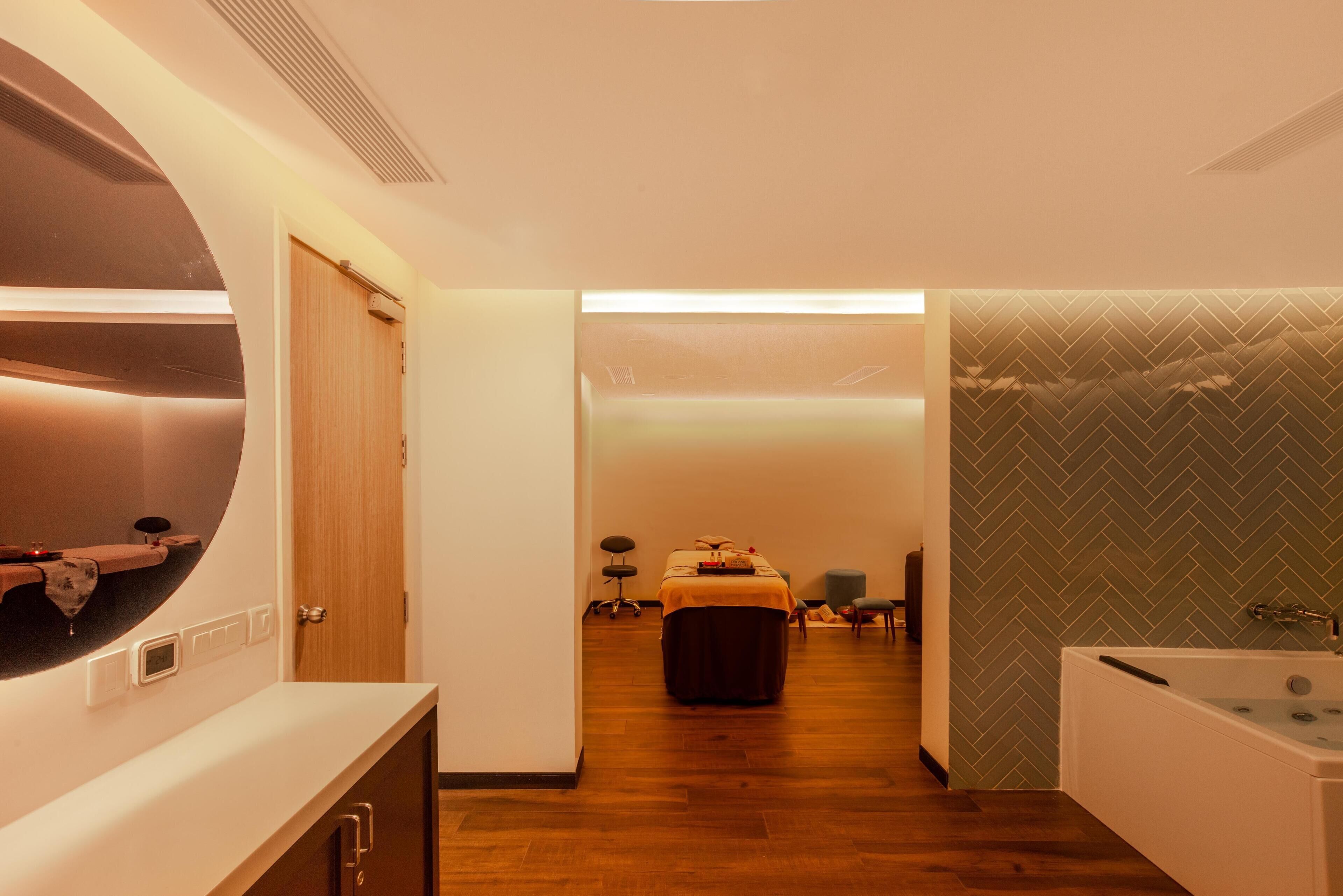 A modern bathroom with a large mirror, a bathtub, and a wooden floor.