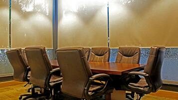 A conference room with a wooden table and six brown leather chairs.