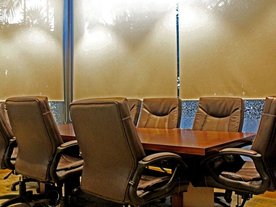 A conference room with a wooden table and six brown leather chairs.