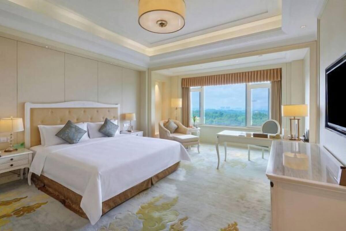 Een hotelkamer met een groot bed, een bureau, een stoel en een televisie.