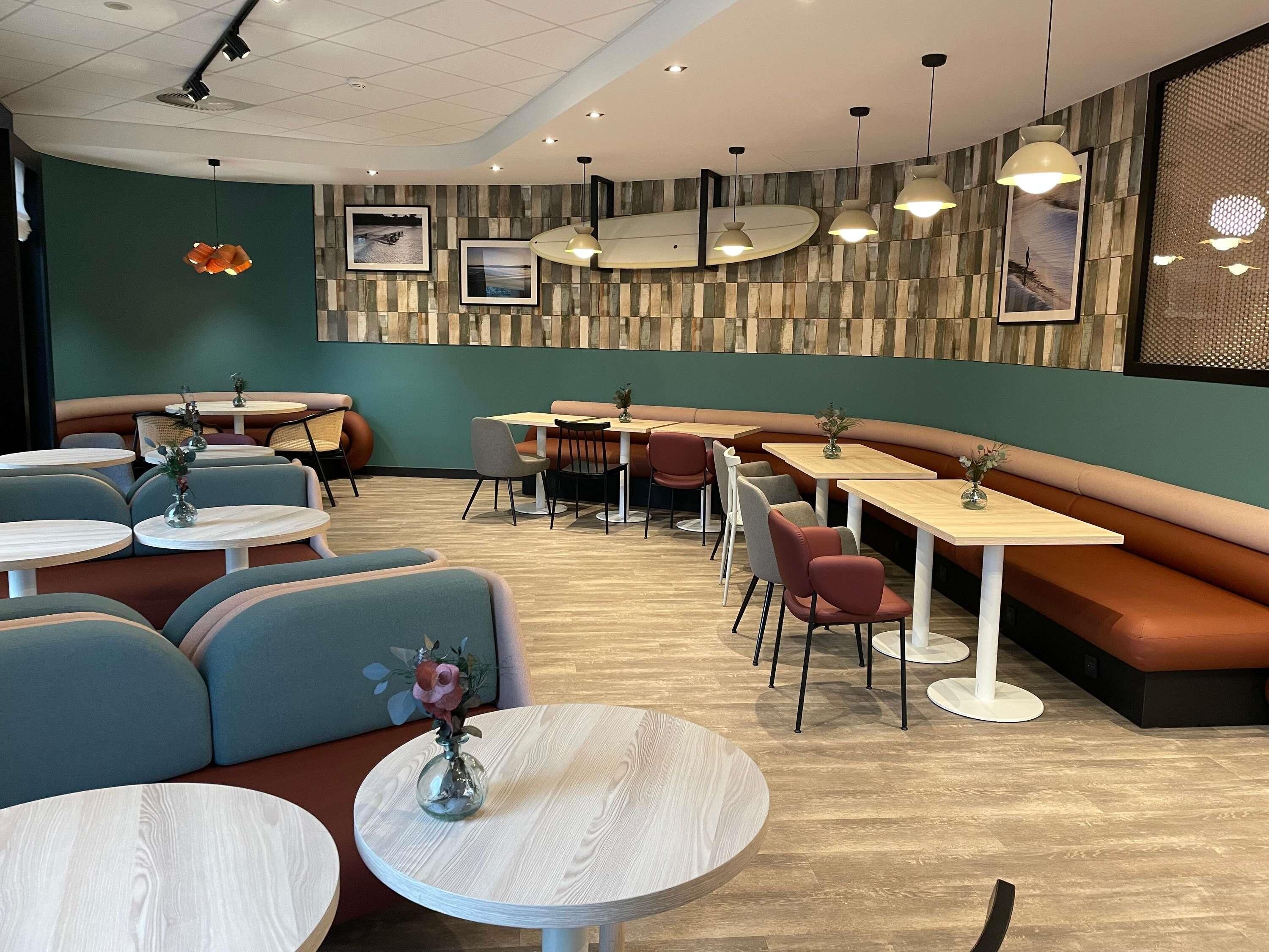En modern restauranginteriör med runda bord, bekväma sittplatser och hängande lampor.