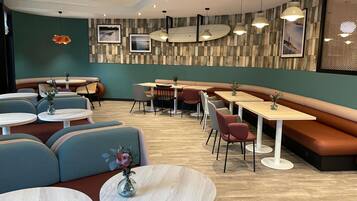 En modern restauranginteriör med runda bord, bekväma sittplatser och hängande lampor.