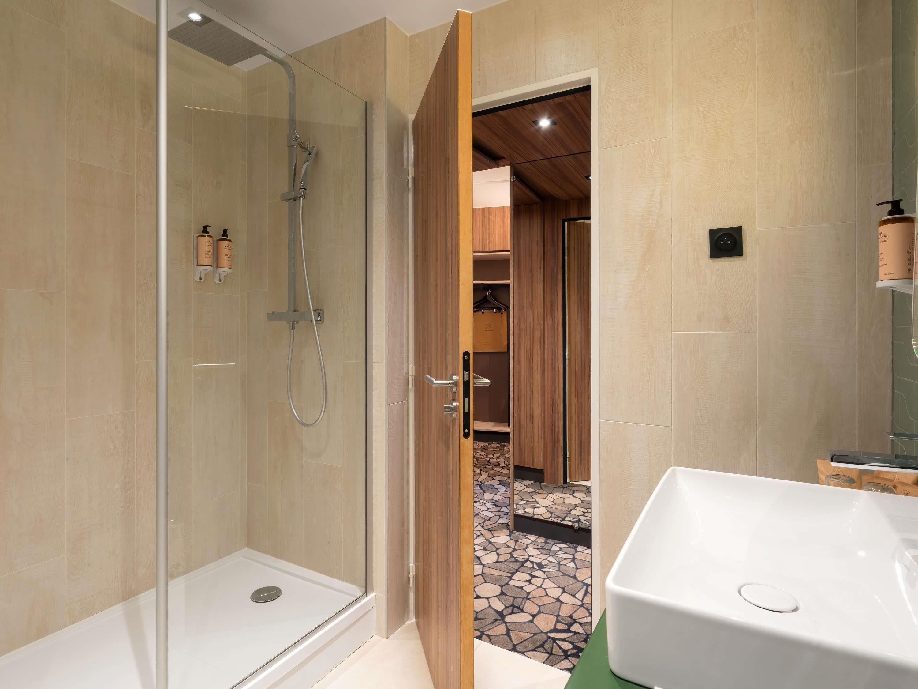 A modern bathroom with a glass shower enclosure, a white sink, and a wooden vanity.