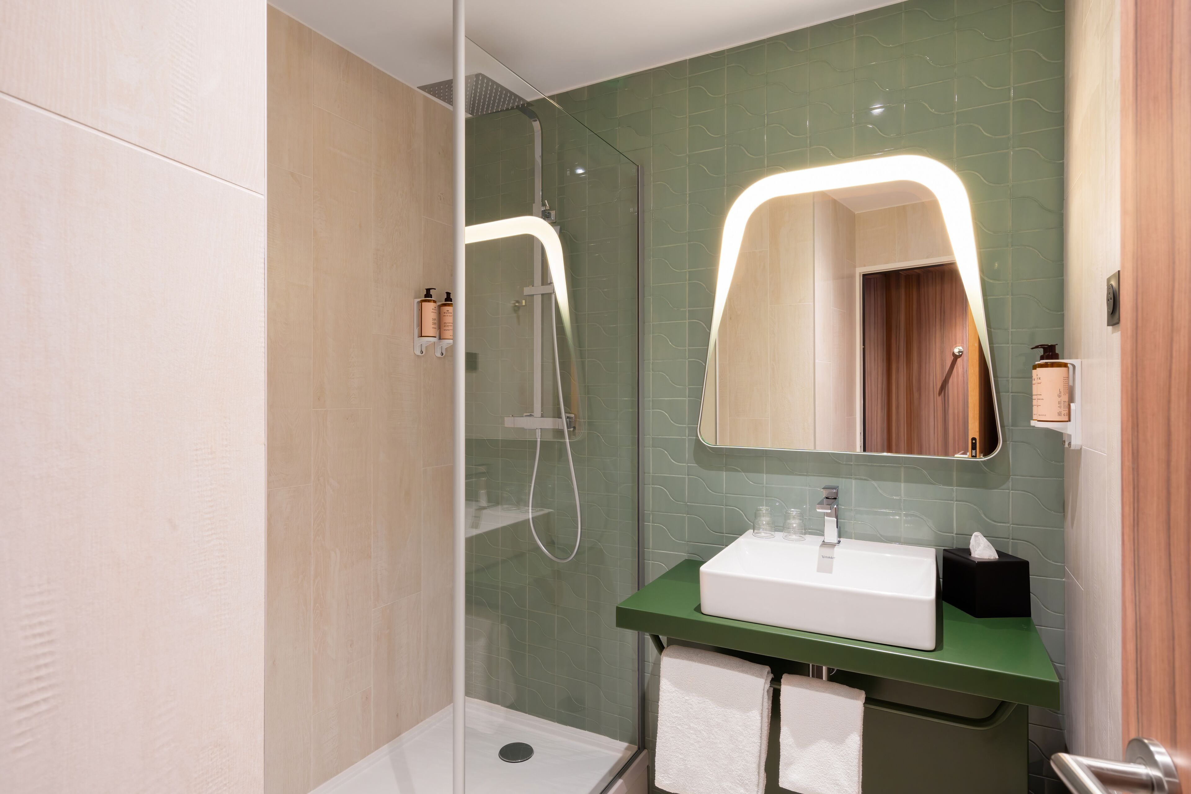 A modern bathroom with a glass-enclosed shower, a green countertop, and a white sink.