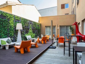 Un espacio al aire libre con mobiliario moderno, una escultura decorativa de jirafa y un jardín vertical.