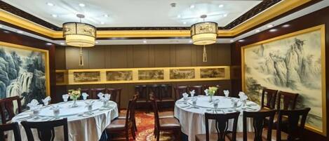 A restaurant with round tables, chairs, and hanging lamps.