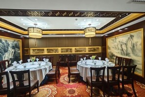 A restaurant with round tables, chairs, and hanging lamps.