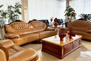 A spacious living room with leather sofas, a wooden coffee table, and potted plants.