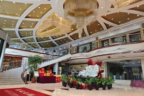 A multi-level shopping mall interior with a grand chandelier, escalators, and a central floral display. - Traffic Business Hotel (Taiyuan)