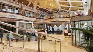 Een meerlaags atrium met een grote kroonluchter, glazen hekwerken en een centrale trap.