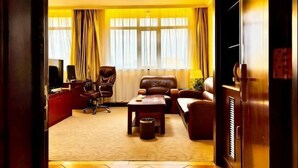 Een hotelkamer met een bank, fauteuil, bureau en een televisie.