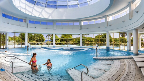 An indoor swimming pool with a glass ceiling, multiple levels, and surrounding greenery. - Hasdrubal Thalassa Port El Kantaoui (Port El Kantaoui)