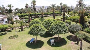 A landscaped garden with palm trees, neatly trimmed bushes, and two lounge chairs. - Hasdrubal Thalassa Port El Kantaoui (Port El Kantaoui)