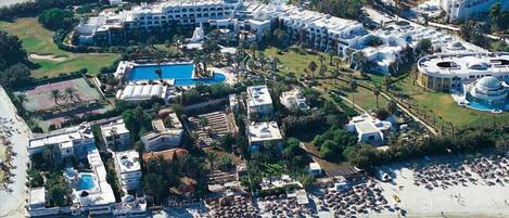 An aerial view of a resort with multiple buildings, a large pool, and a beach area.