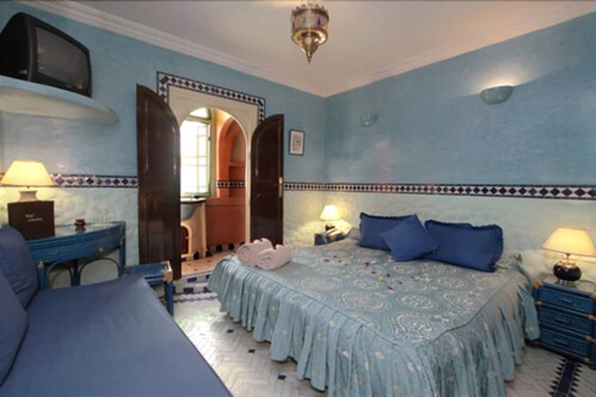 Une chambre à coucher comprenant un lit, deux tables de chevet, un bureau et une chaise.