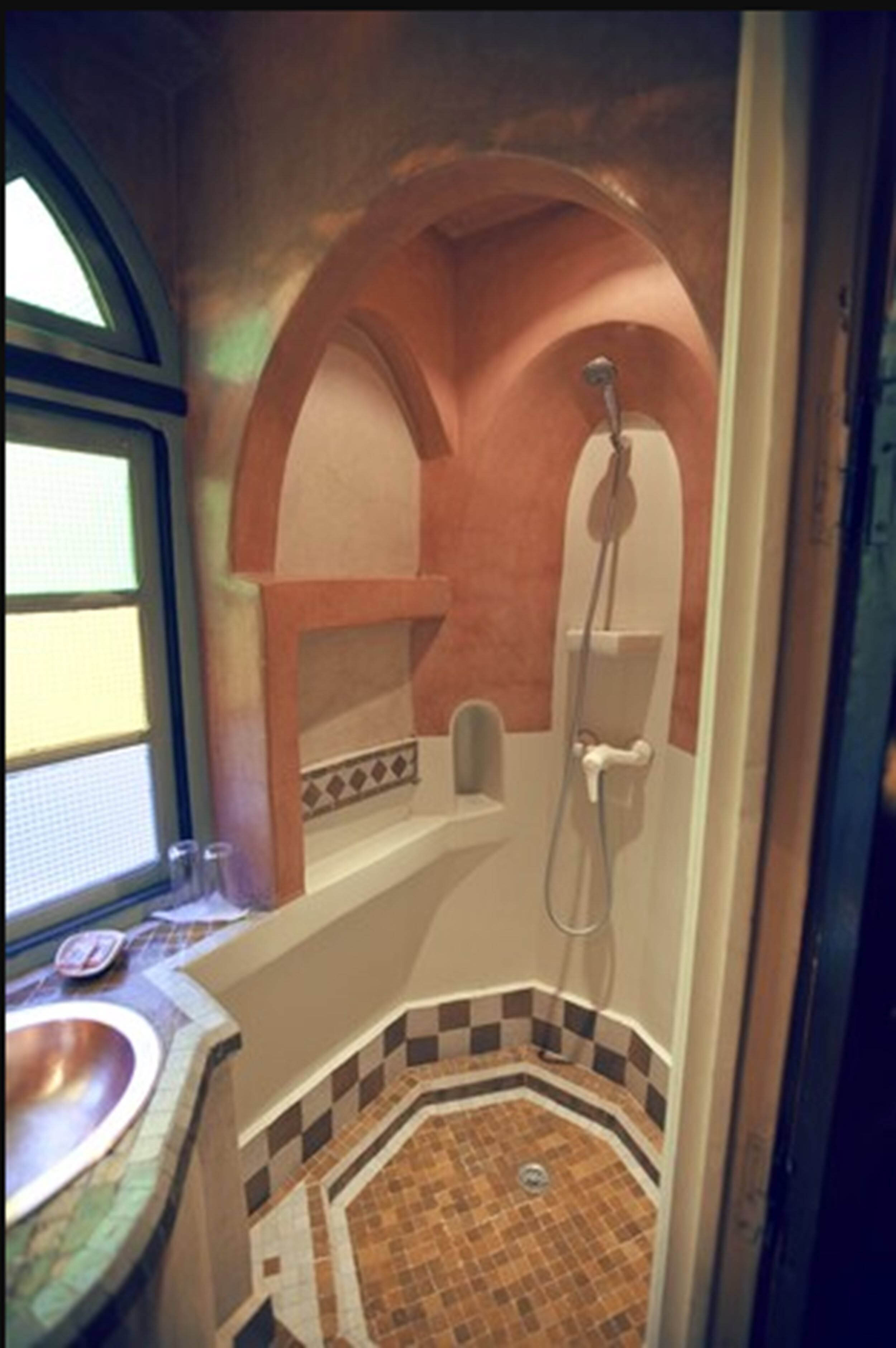 A bathroom with a tiled floor, a sink, and a shower area.