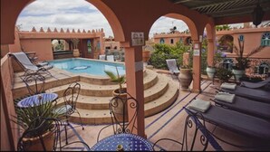 A pool area with lounge chairs, a table, and potted plants. - Riad Catalina (Marrakech)