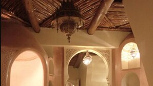 A traditional Moroccan-style bathroom with a curved bathtub, a large mirror, and a wooden vanity with drawers. - Riad Catalina (Marrakech)
