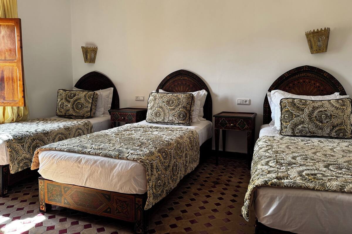 A room with two beds, each with a patterned bedspread and matching pillows, a wooden headboard, and a decorative wall piece.