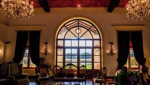Una habitación amplia con un gran ventanal de arco, elegantes candelabros y asientos cómodos.