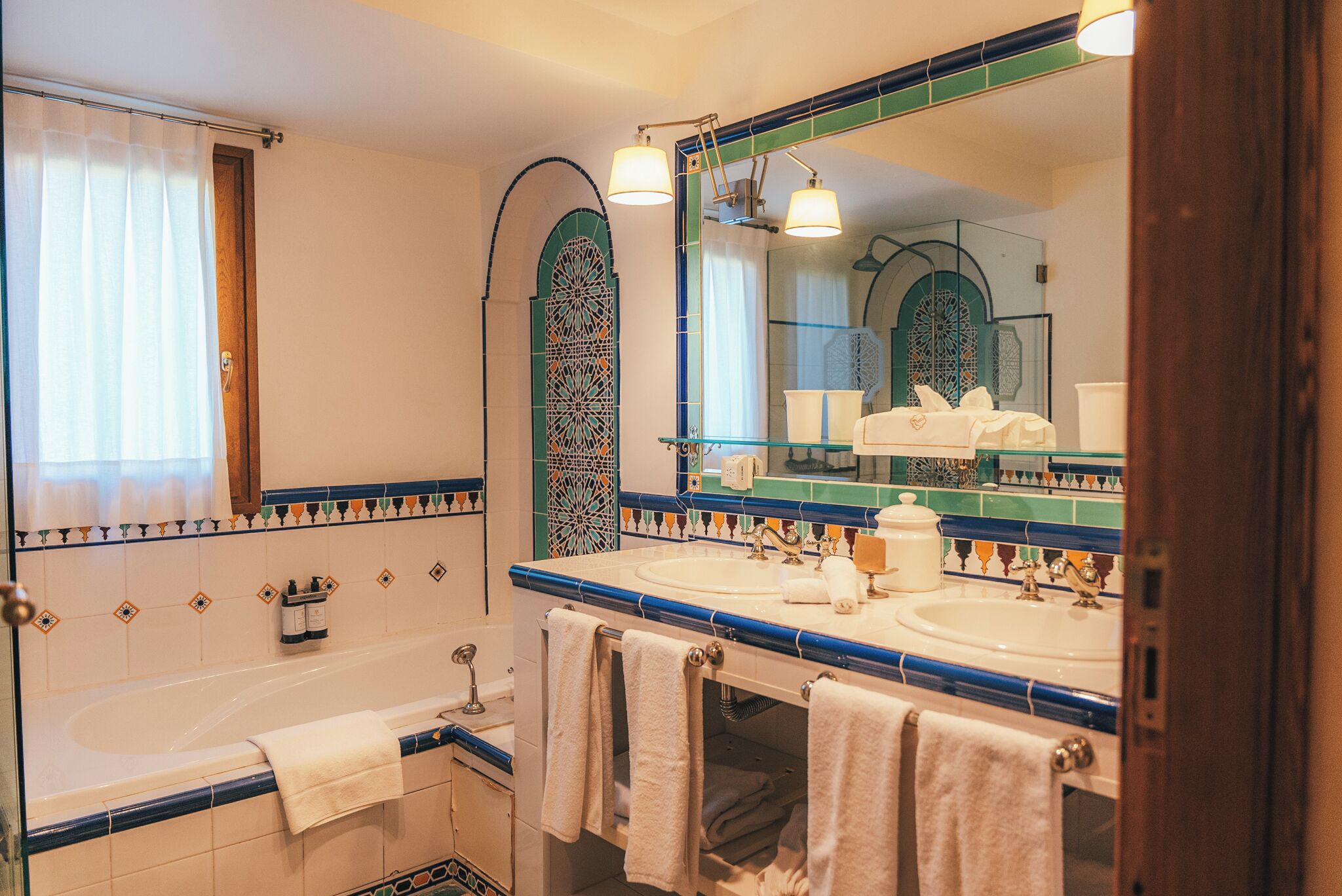 Een badkamer met twee wastafels, een badkuip en een grote spiegel.